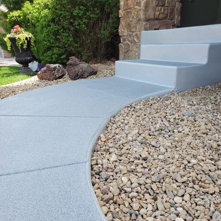 A sidewalk with stairs and gravel in front of a house.