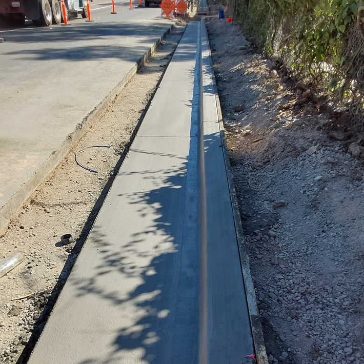 A concrete curb is being built on the side of a road