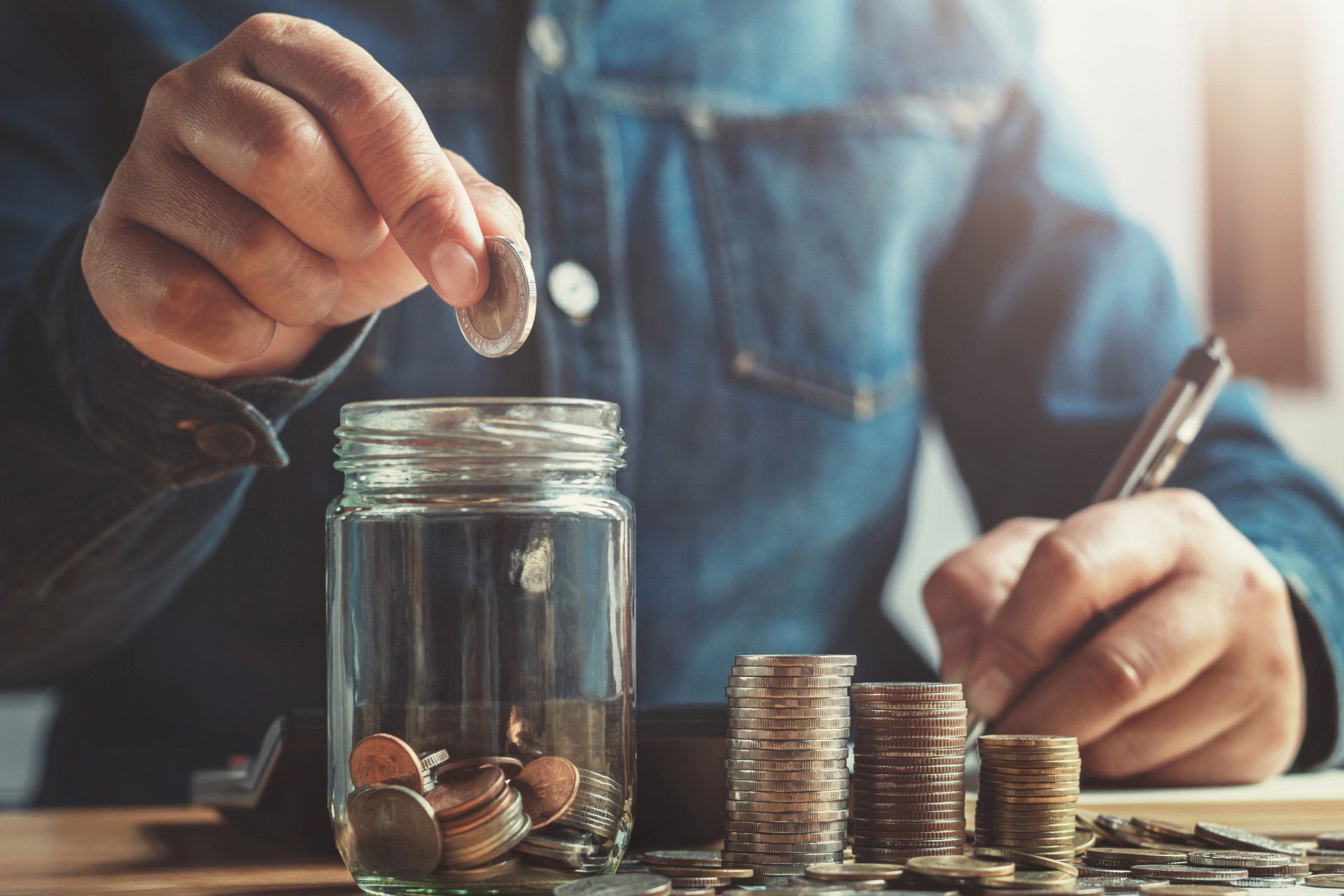 person putting coins into a jar for savings