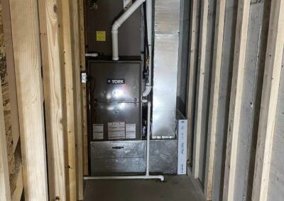 A furnace is installed in a room in a house under construction.