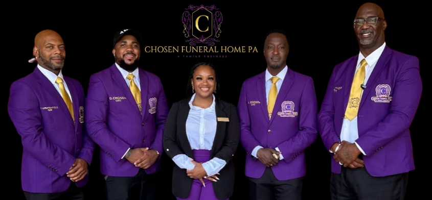 Five people standing in a row against a black background, wearing purple blazers with gold ties and a funeral home logo.