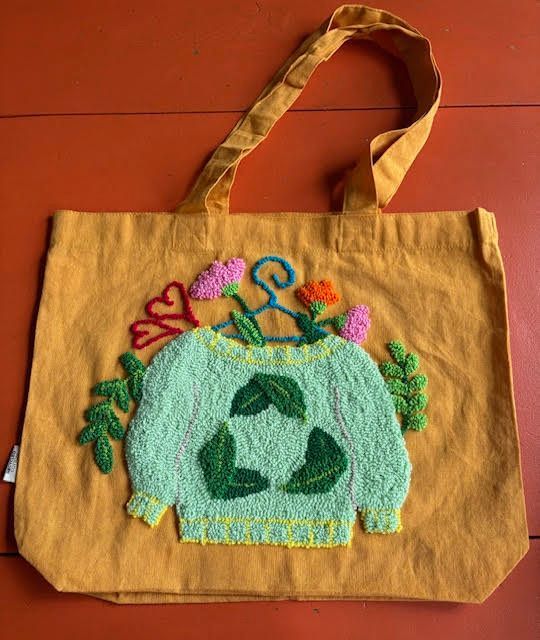 Gele draagtas met een groen trui-ontwerp en bloemenaccenten, gecentreerd op de voorkant.