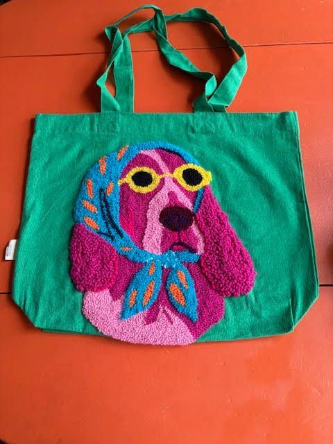 Groene draagtas met een roze en witte hond die een hoofddoek en zonnebril draagt.