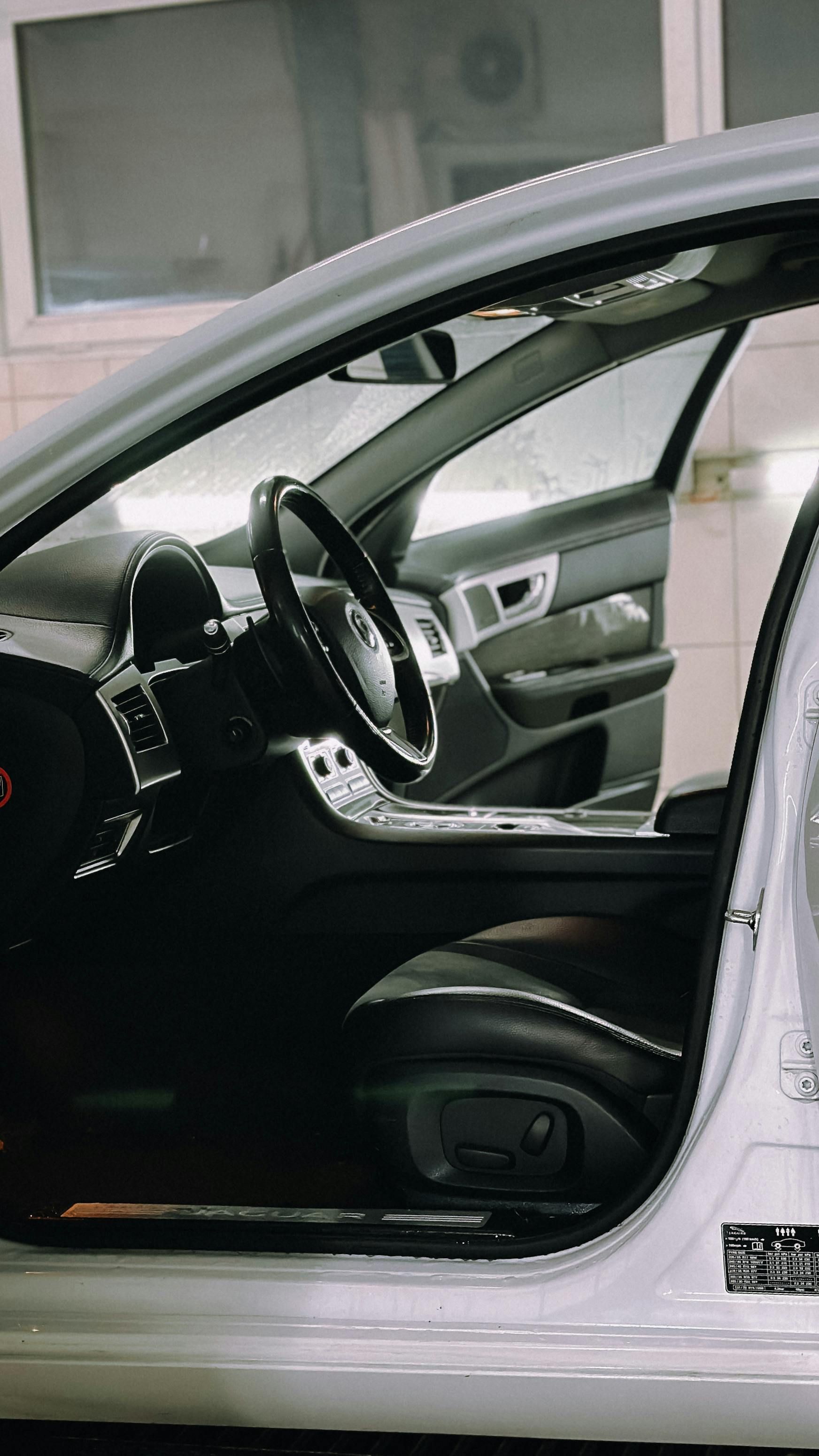 A white car with the door open is parked in a garage.