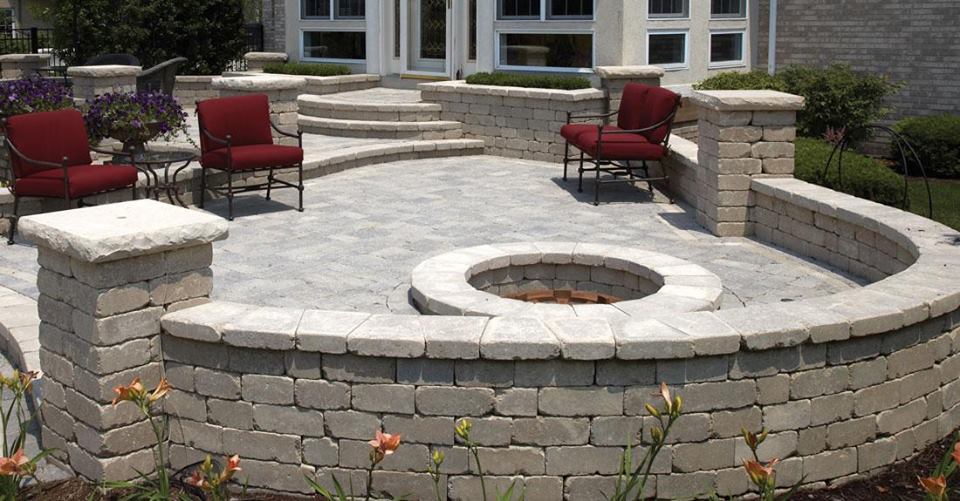 Stone patio with fire pit, seating, and decorative walls.