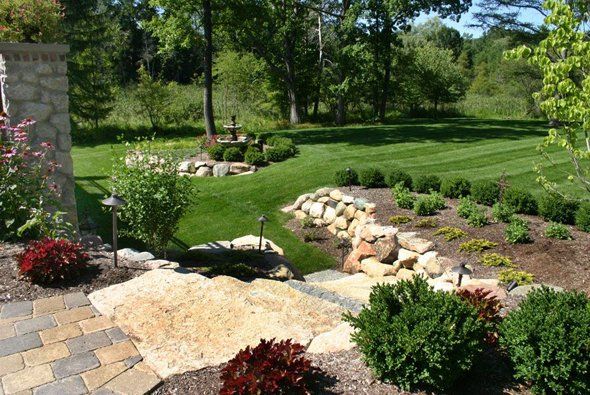 Grassy area with nice rocky landscaping with small bushes — Clarkston, MI — Lowries Landscape Inc