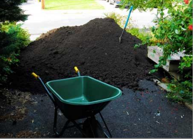 A wheelbarrow sits in front of a pile of dirt A wheelbarrow sits in front of a pile of dirt