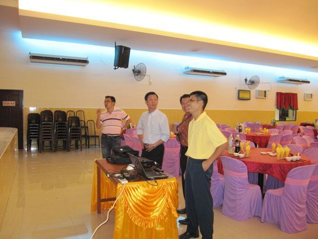 一群男人站在一间摆满桌椅的大房间里