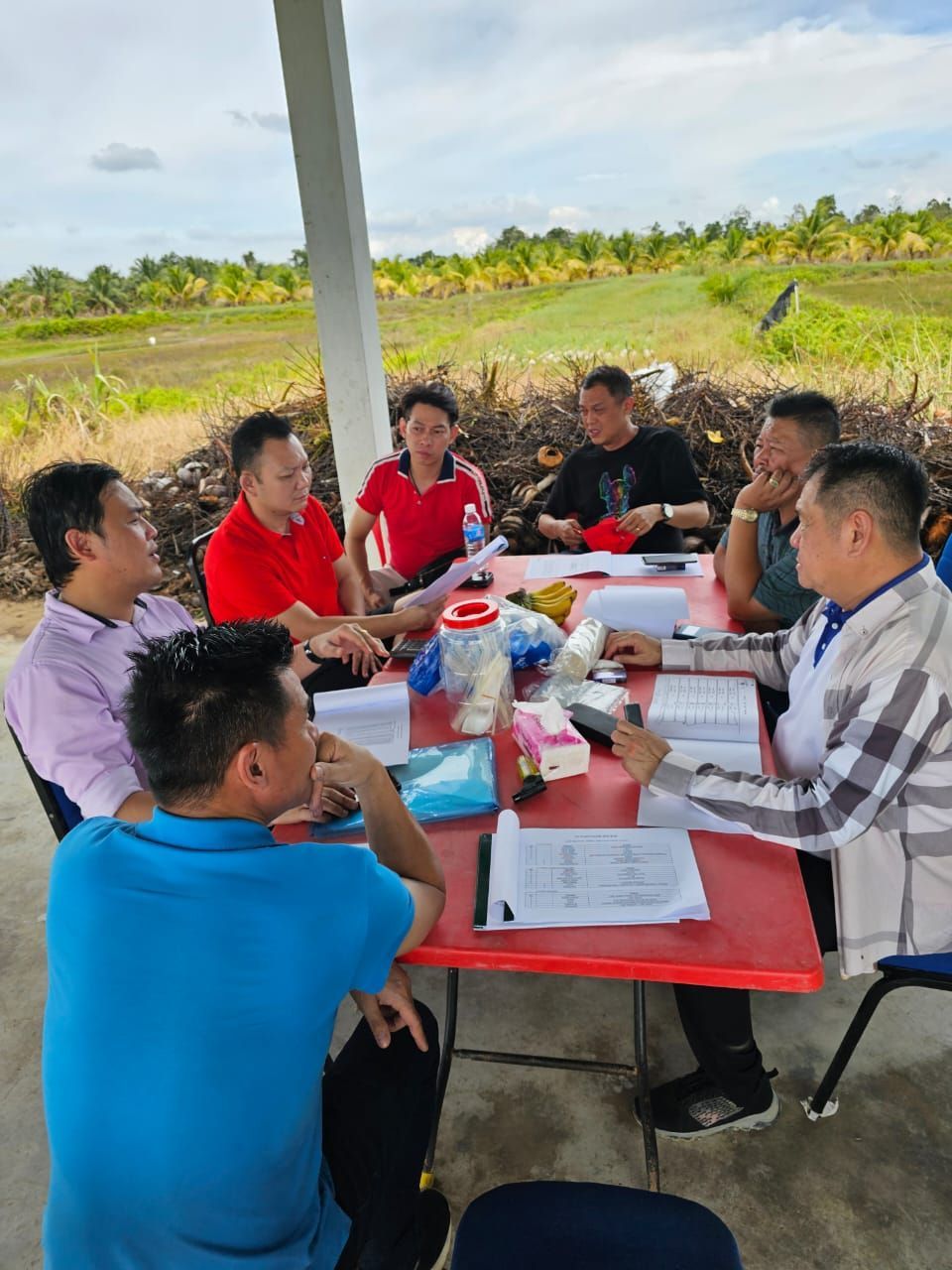 一群男人正围坐在田野里的一张桌子旁。