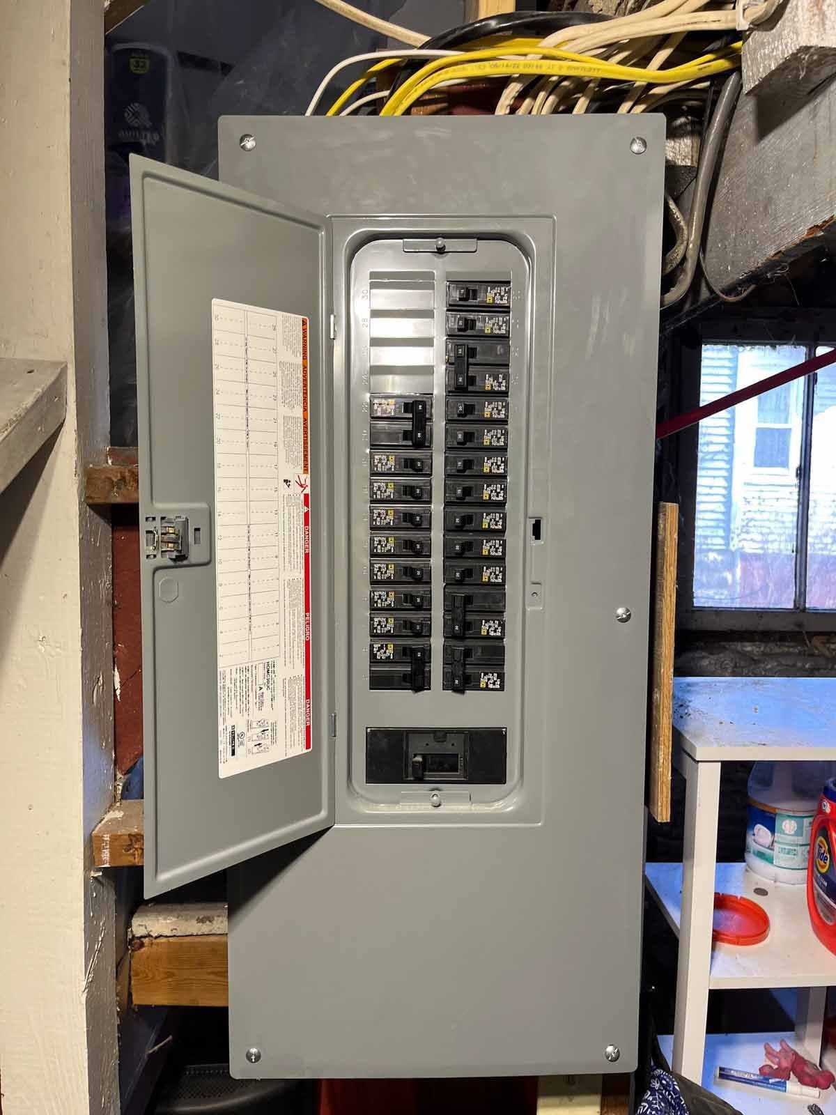 A electrical panel is sitting on a wall in a room with the door open.