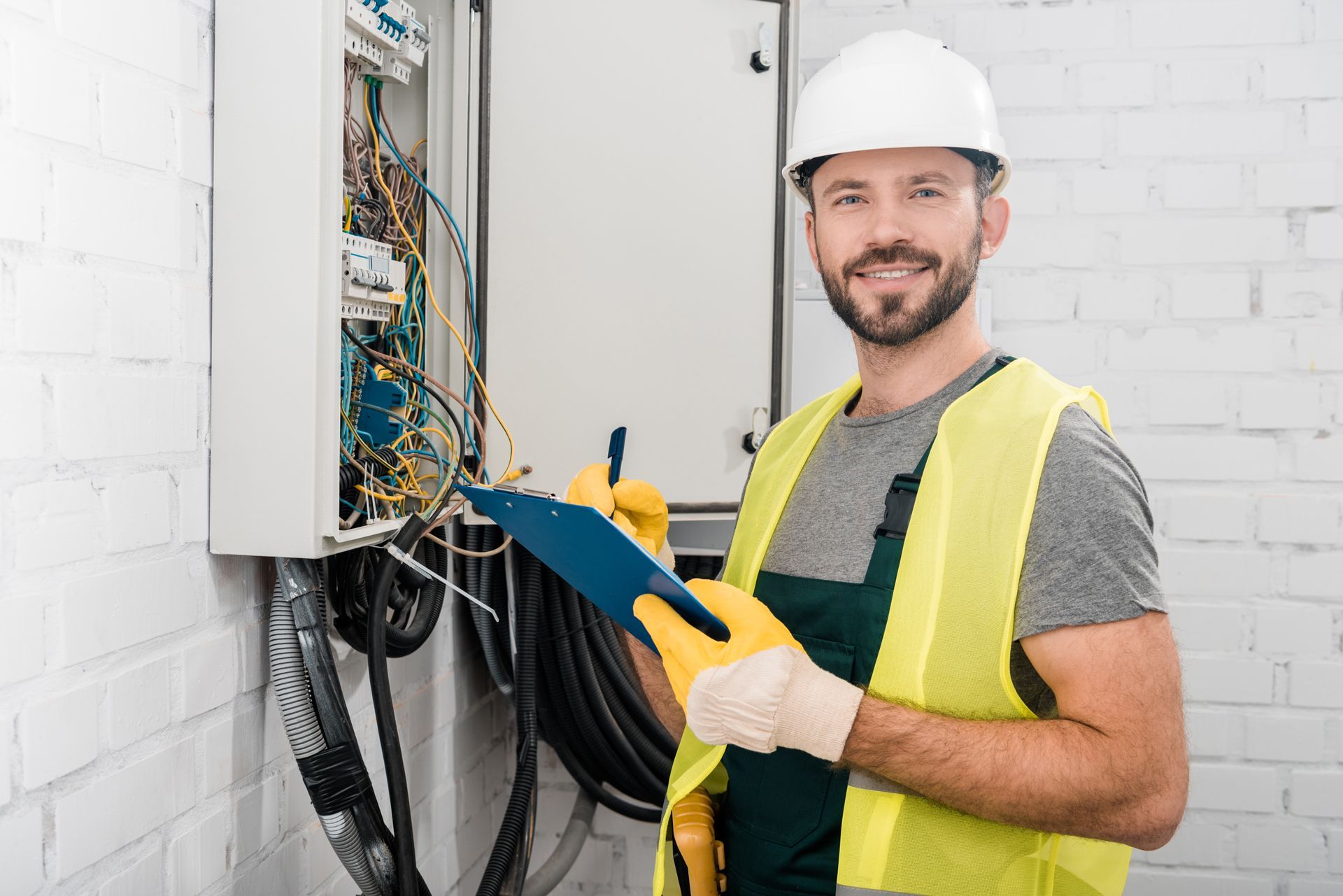 An Electrician is Holding a Clipboard in Front of an Electrical Box