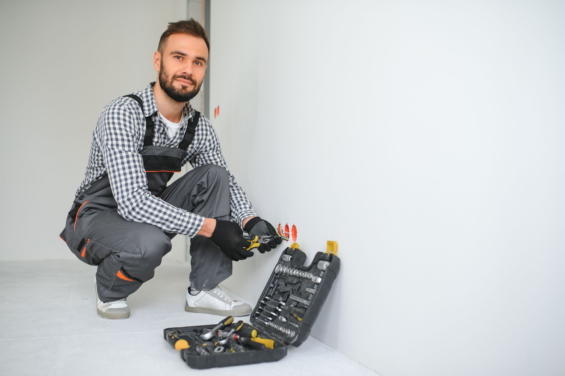 A Man is Kneeling Down Next to a Box of Tools