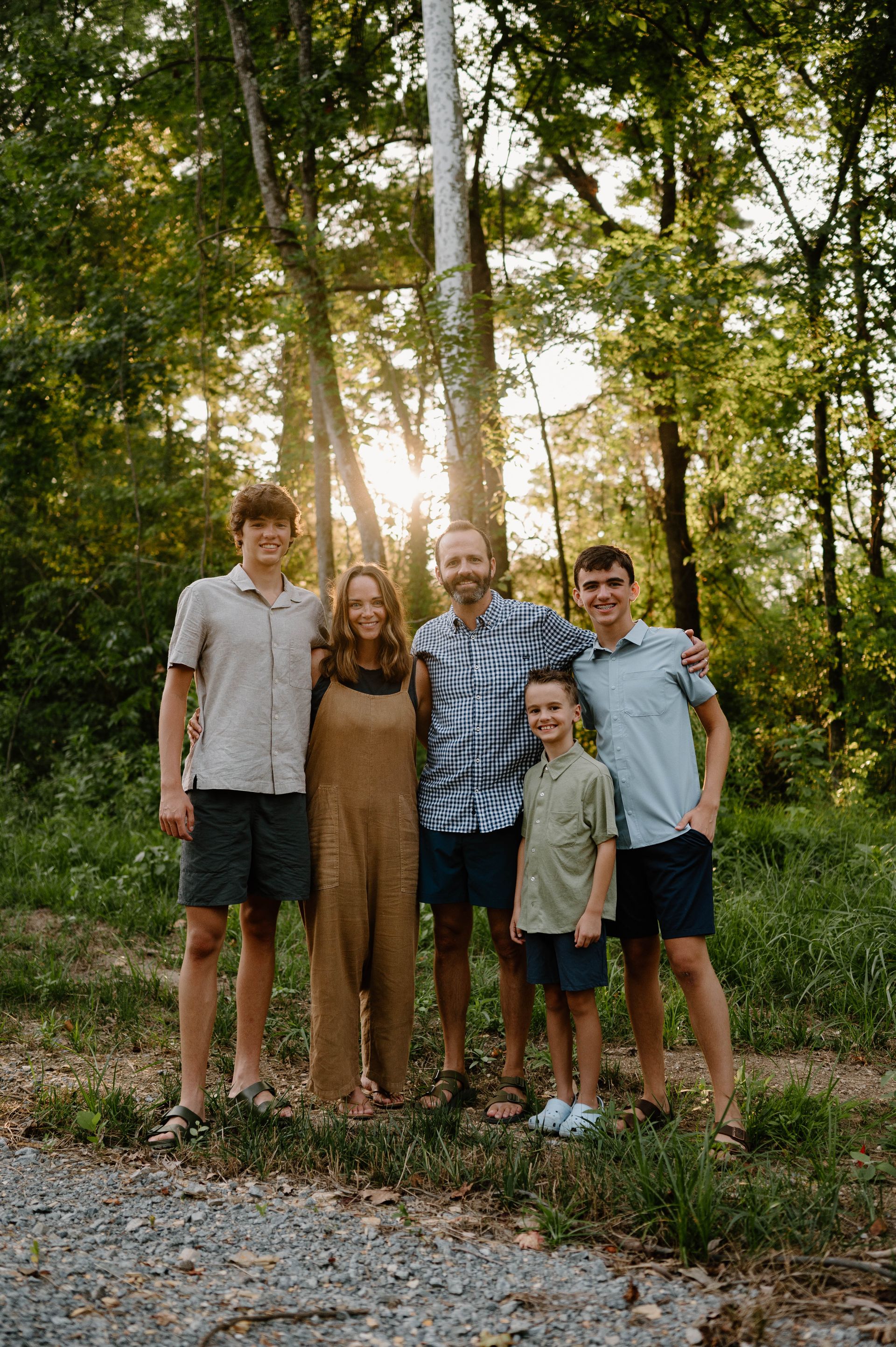 A family is posing for a picture in the woods.