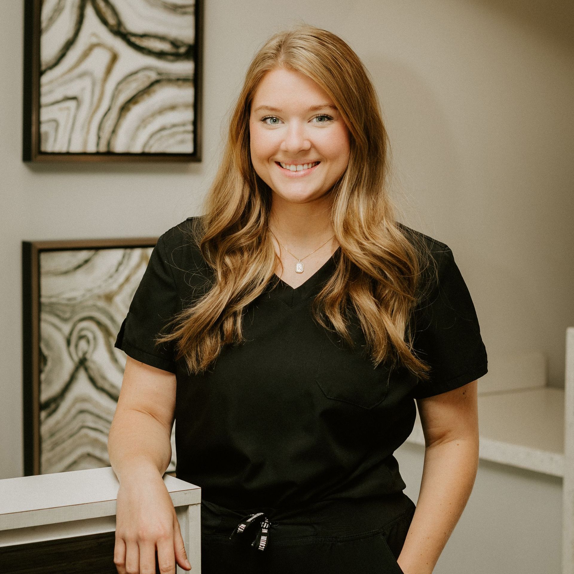 A woman in a black scrub top is smiling for the camera.