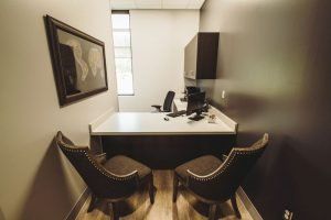 A small office with two chairs and a desk.