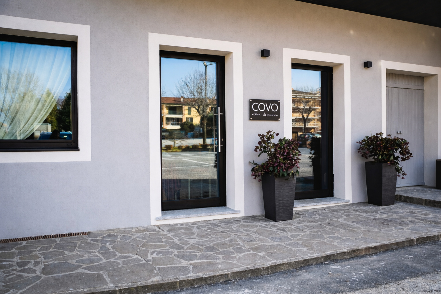 La facciata di un edificio grigio chiaro presenta due porte a vetri