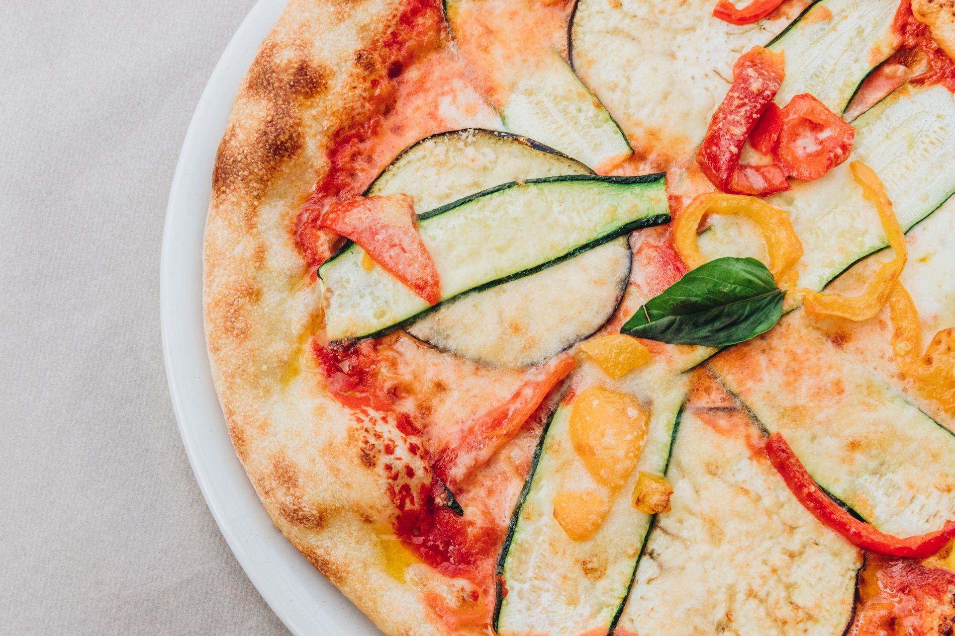 Primo piano di una pizza condita con zucchine a fette, peperoni