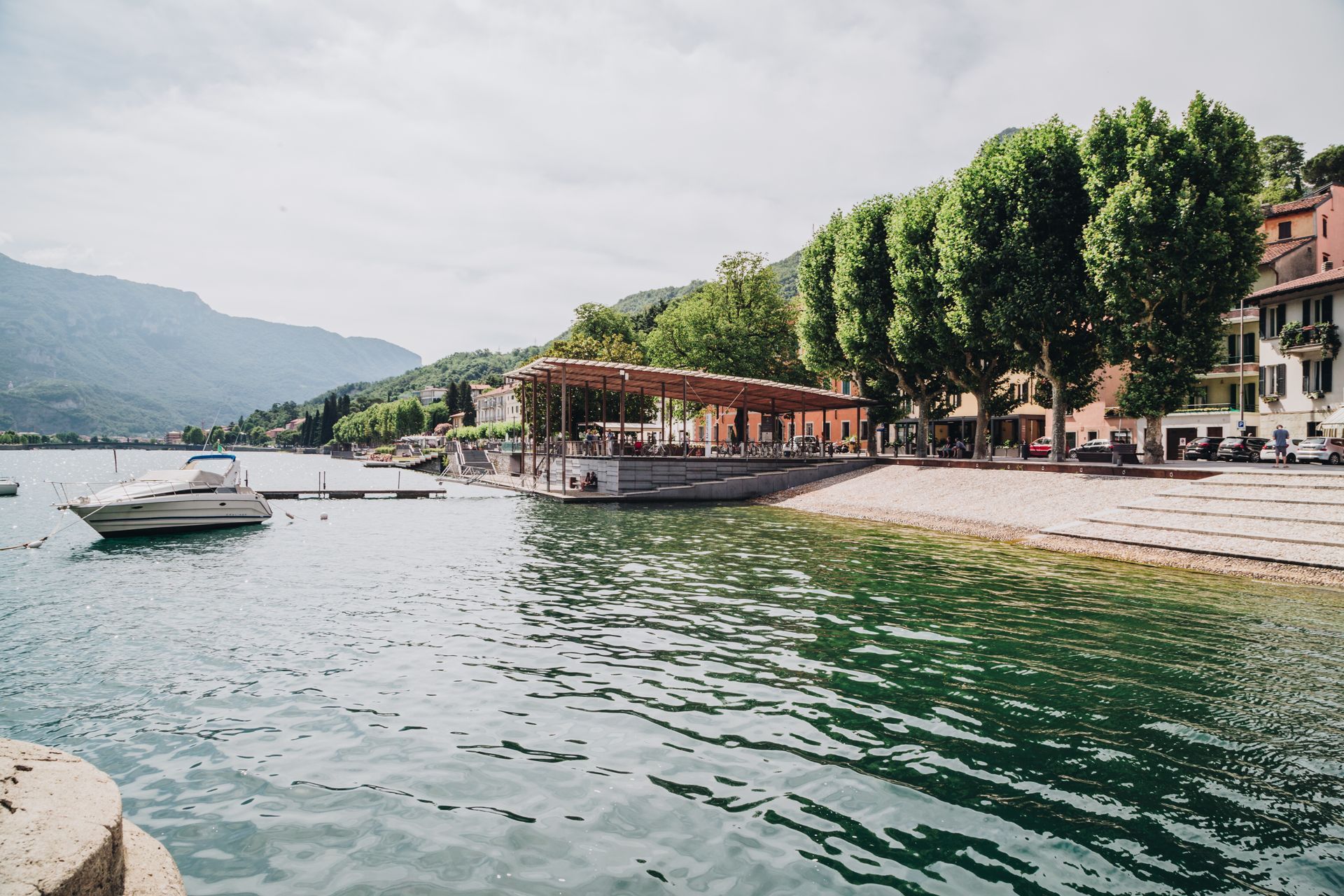 Una barca attracca accanto a un patio in riva al lago e agli alberi in una pittoresca cittadina 
