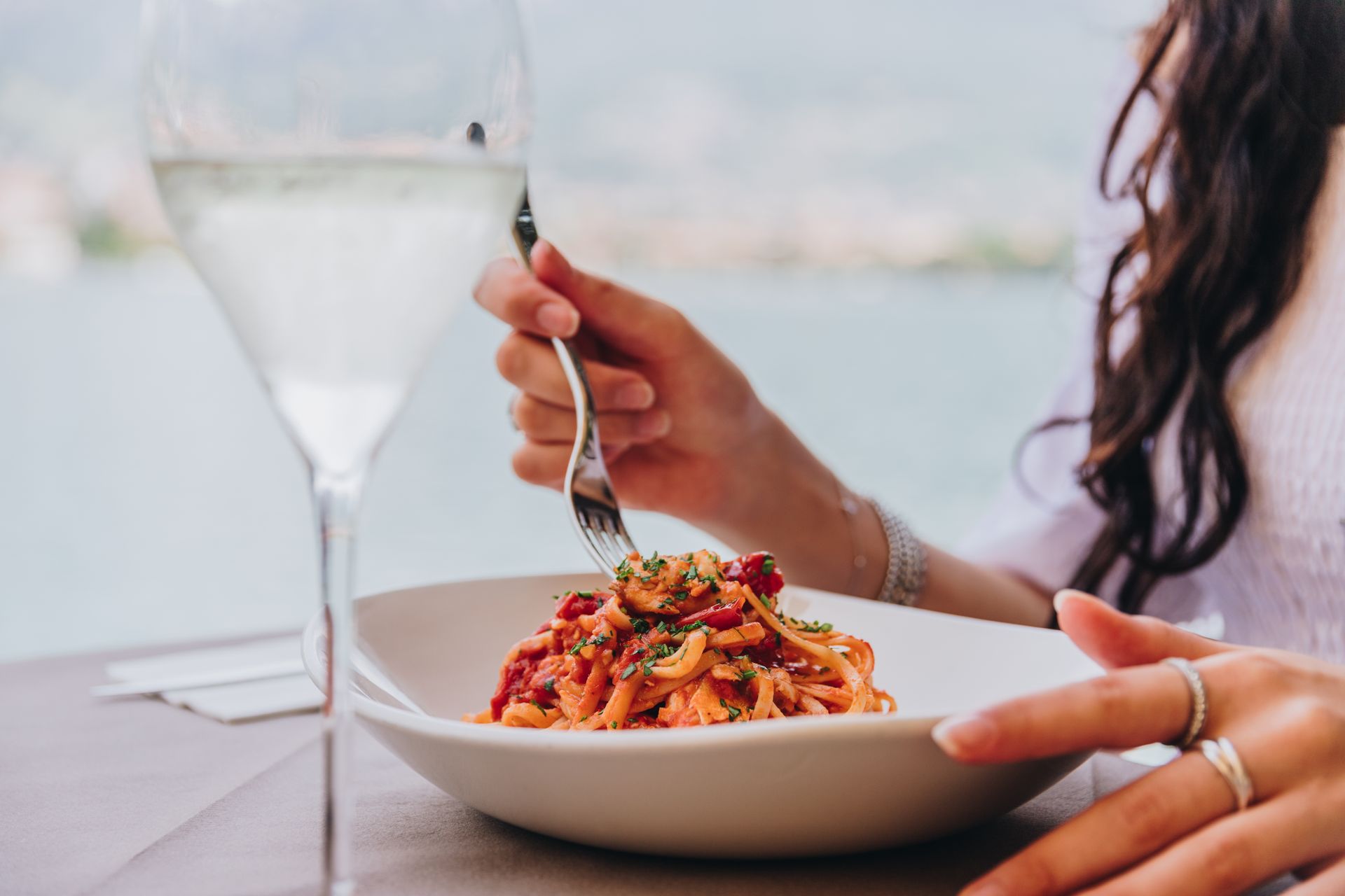 Posti a sedere all'aperto nel ristorante con fioriere in metallo, tavoli e vista sul lago.