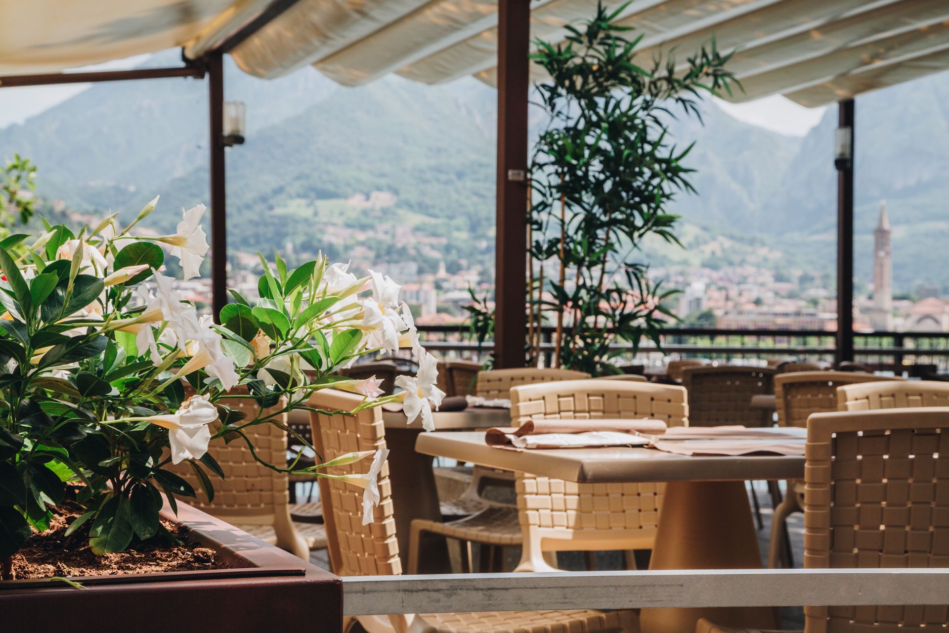 La terrazza di un ristorante, arredata con sedie e tavoli in vimini beige