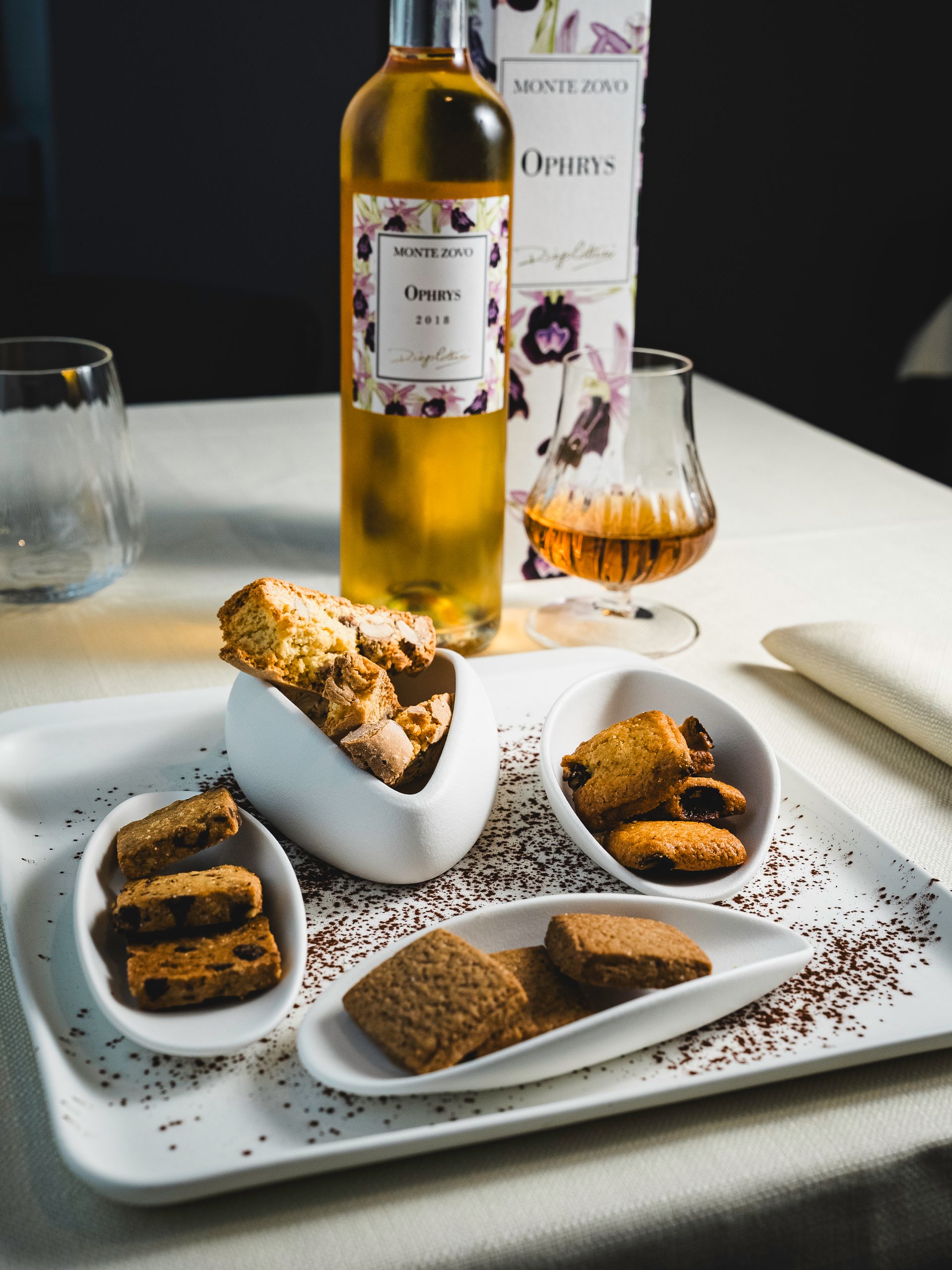 Una bottiglia di vino e un bicchiere da brandy, insieme a un vassoio di biscotti.