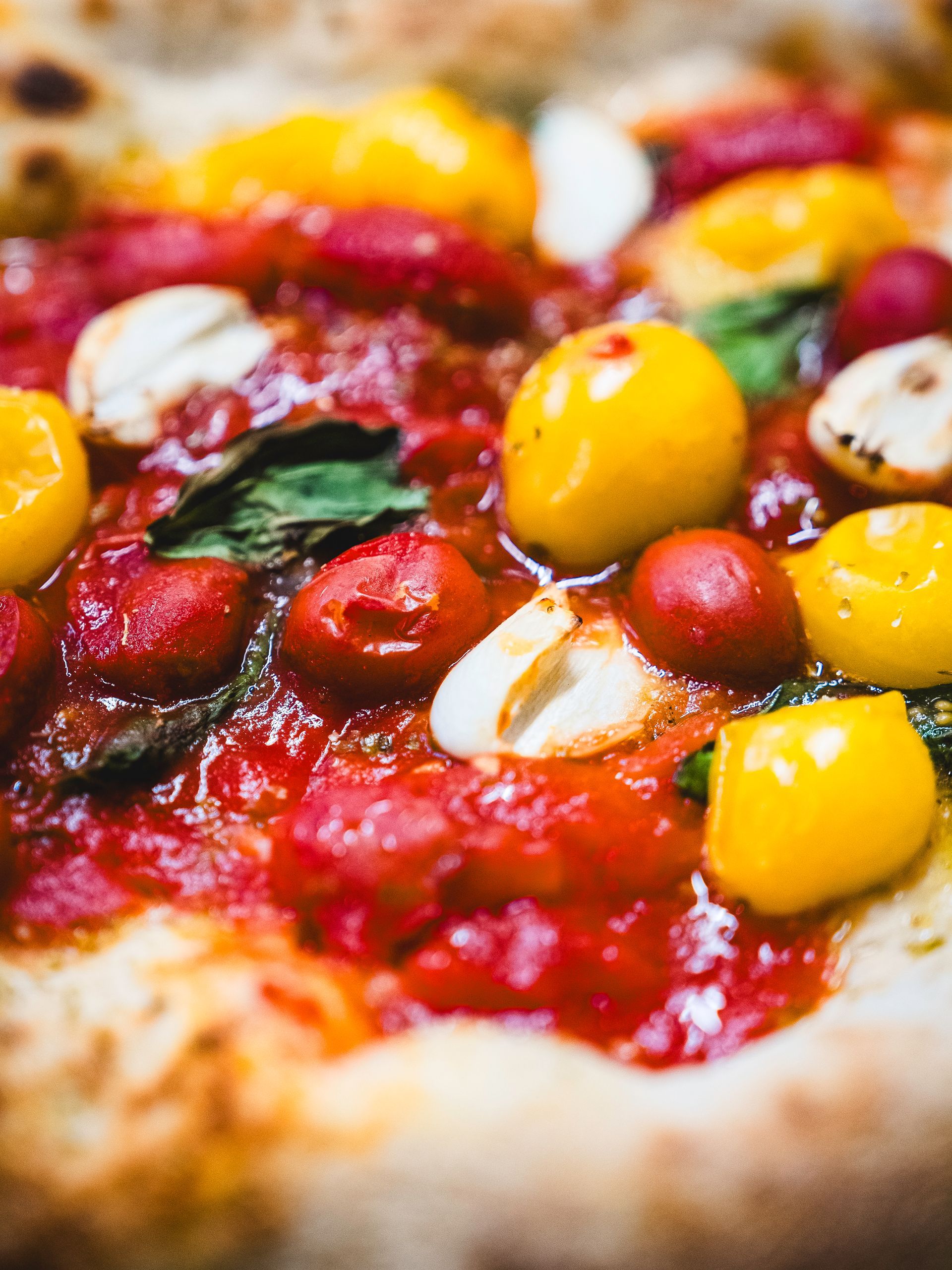 Pizza condita con pomodorini gialli e rossi, mozzarella e basilico.