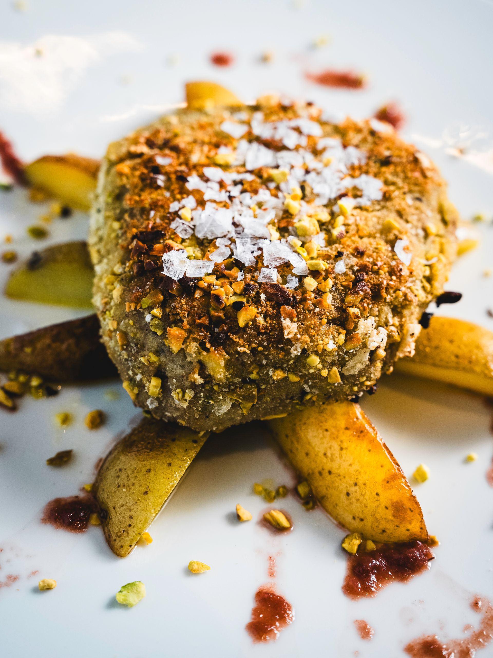 Piatto principale con crosta, fette di pera e salsa su un piatto bianco.