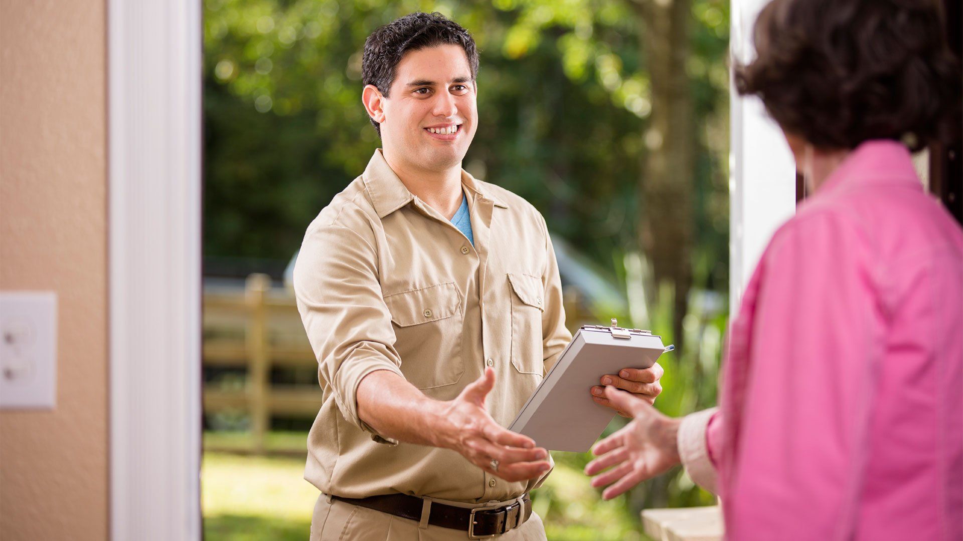 A man is shaking hands with a woman while holding a clipboard.