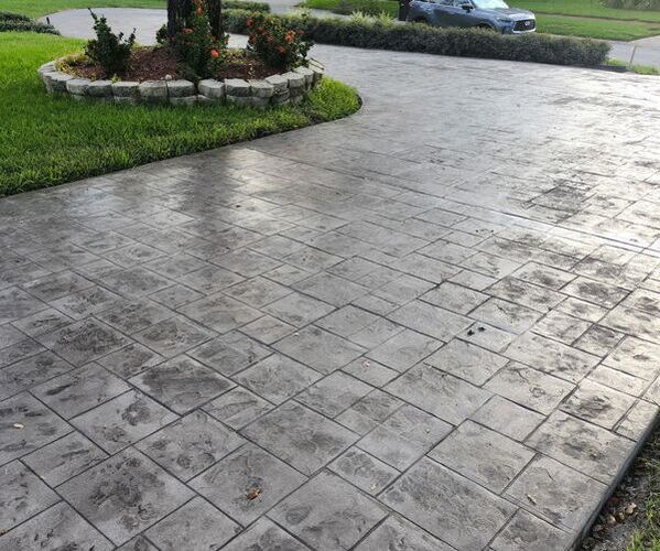 Gray stamped concrete driveway, with grass and landscaping.