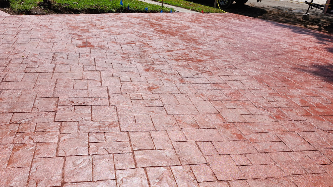 Red stamped concrete driveway with a brick pattern.