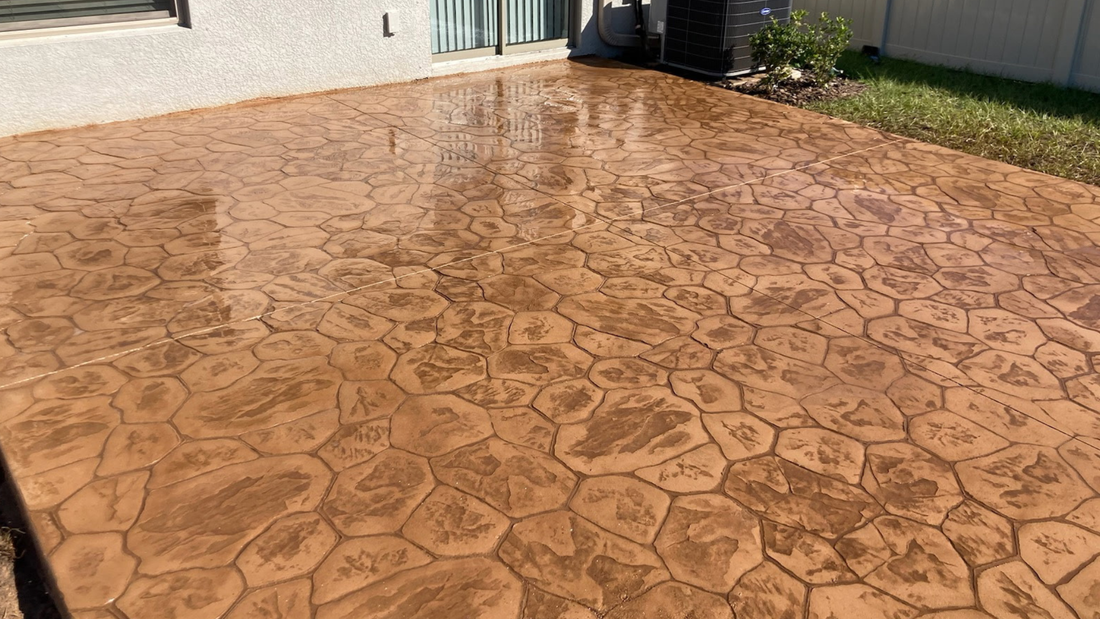Brown, stamped concrete patio with cobblestone pattern reflecting light.
