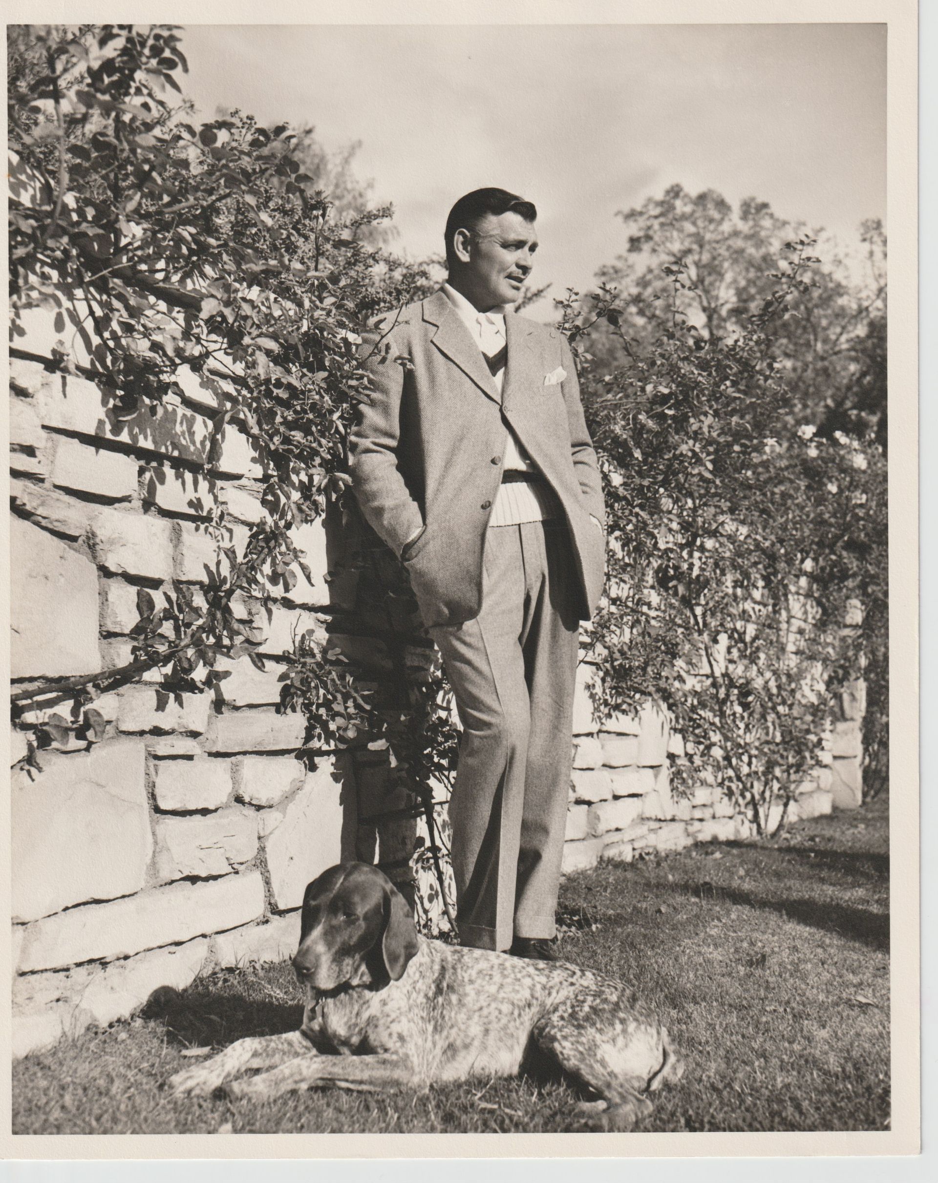 A man in a suit standing next to a dog