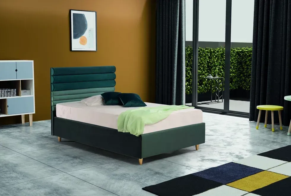 C'è un letto in mezzo alla stanza con un quadro sul muro.