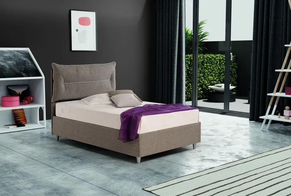 C'è un letto in mezzo alla stanza con una coperta viola sopra.