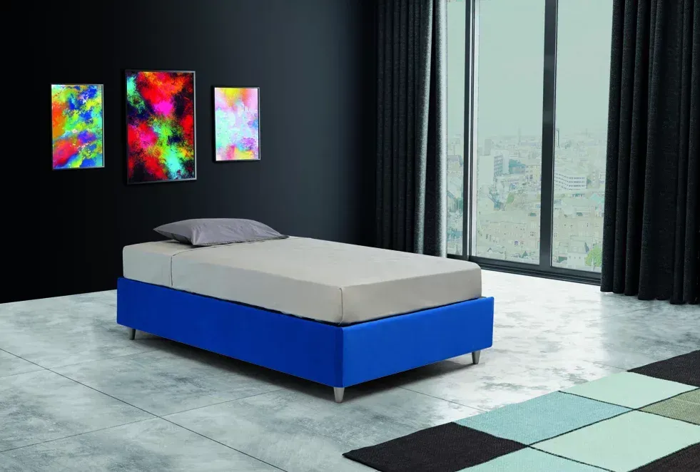 Un letto con una cornice blu è posizionato in una stanza accanto a una finestra.