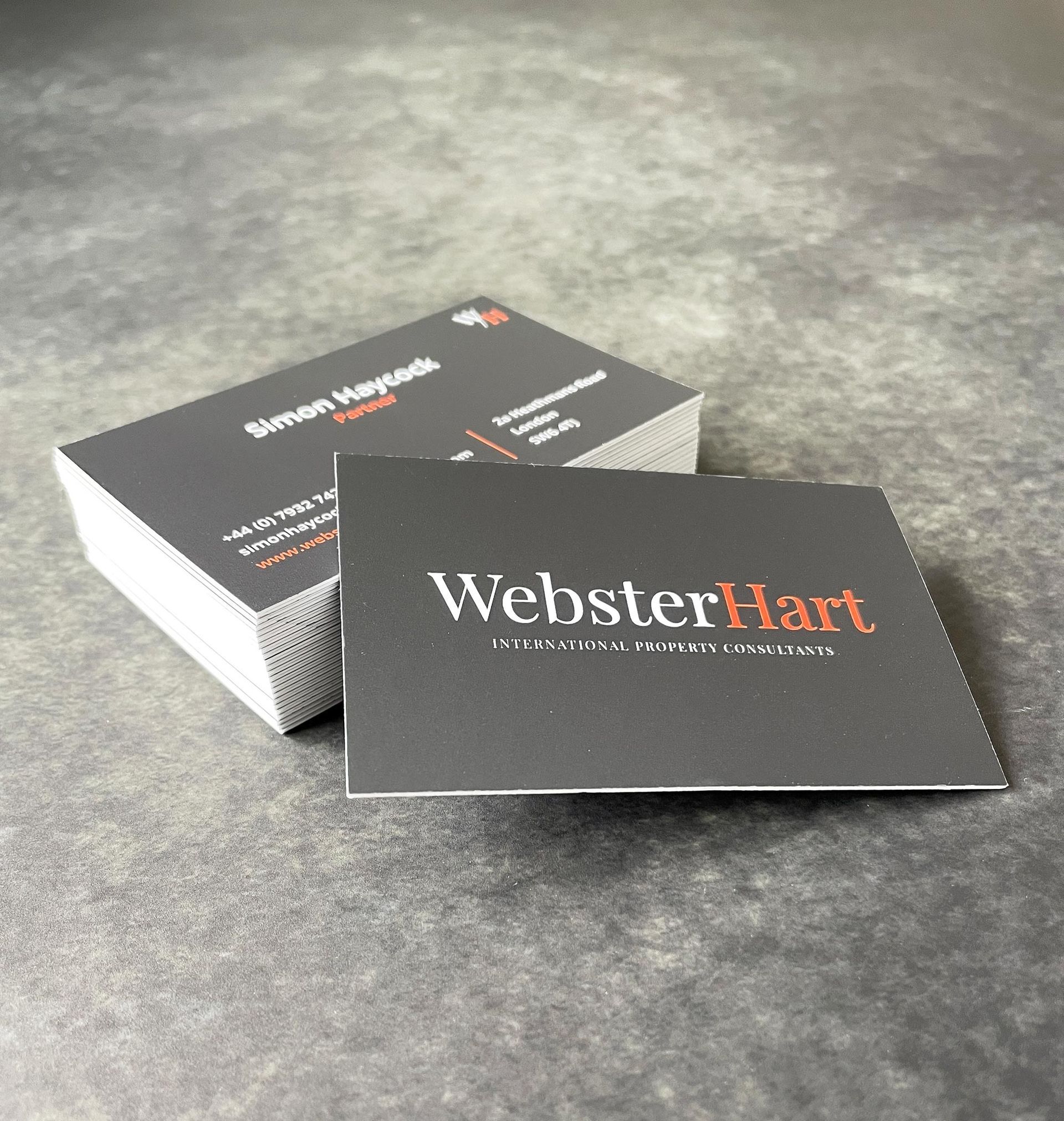 A stack of dark gray business cards, one card in front, showing the