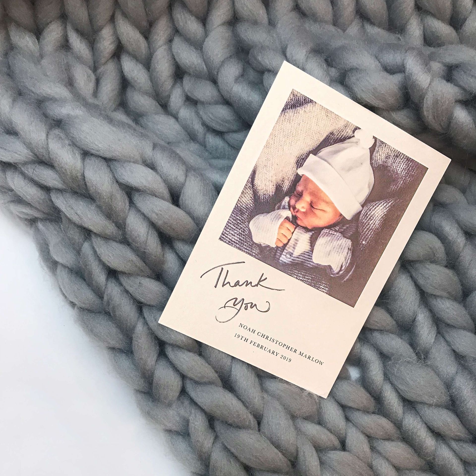 Thank you card with sleeping baby on gray chunky knit blanket.