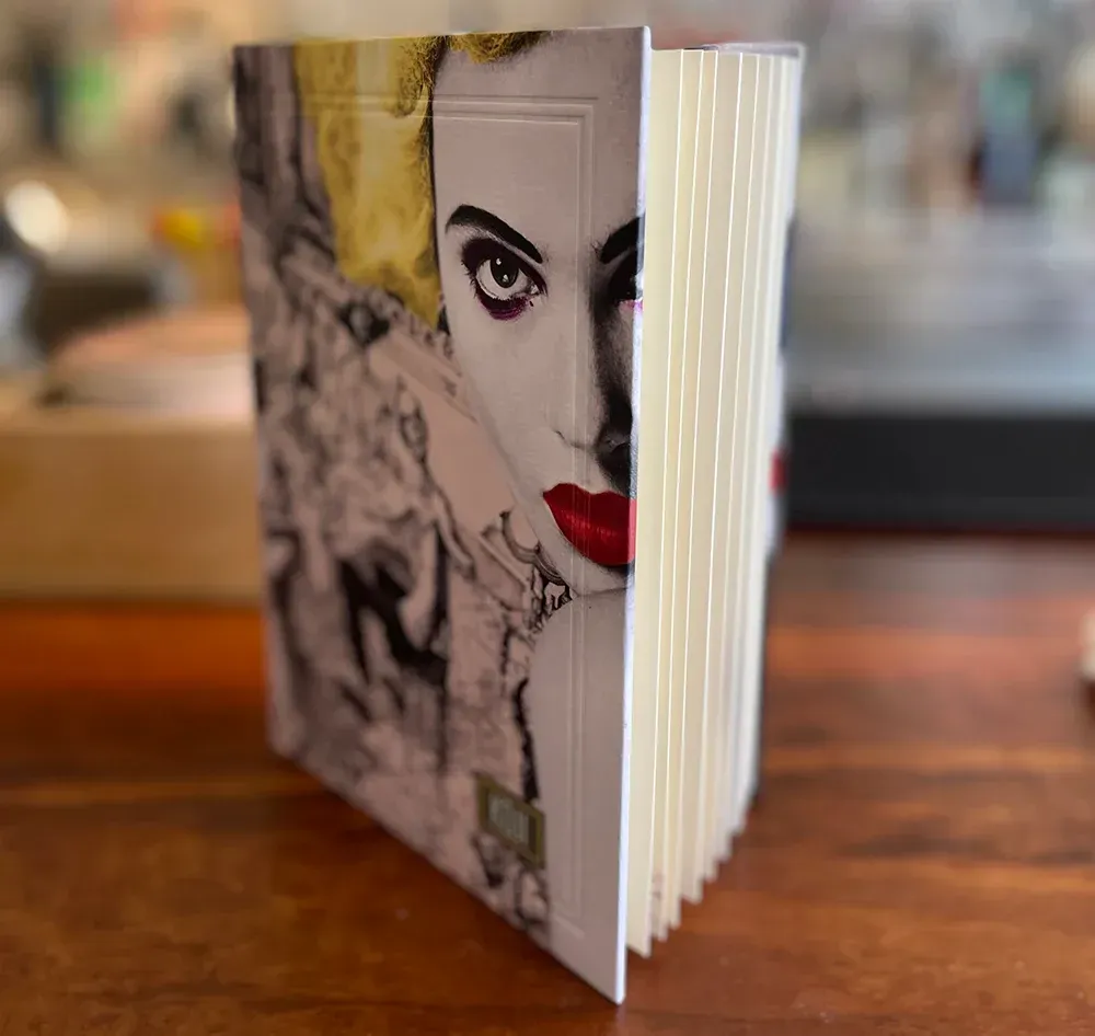 Book with a woman's face on the cover, red lips, side view, on a wooden surface.