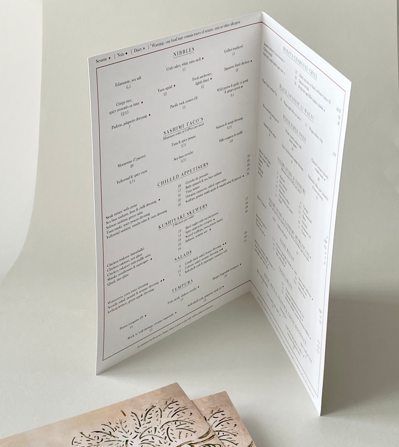 Tri-fold menu on a white surface; lists food items in black text.