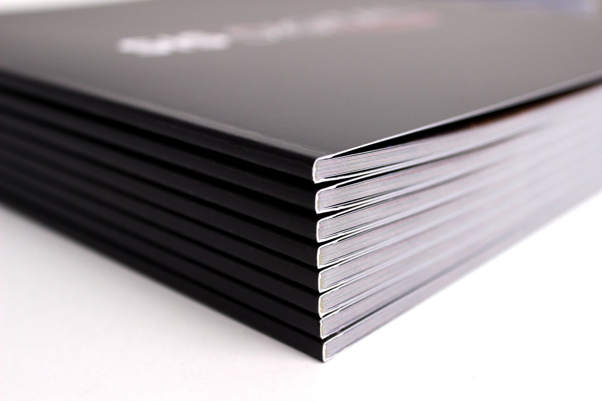 Stack of black books, glossy covers, on a white surface.
