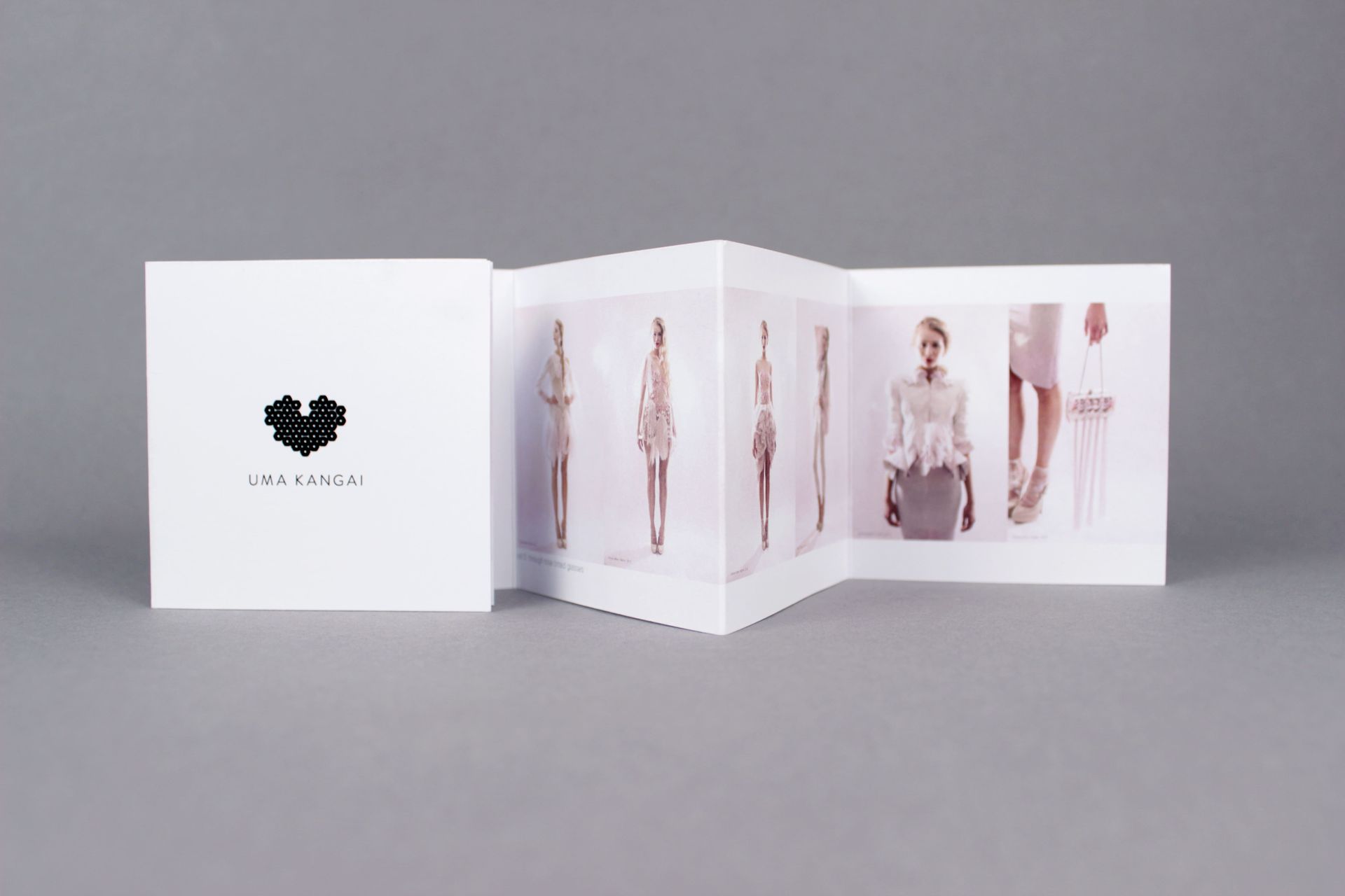 A white, accordion-style booklet displaying fashion photos, with a logo on the cover.
