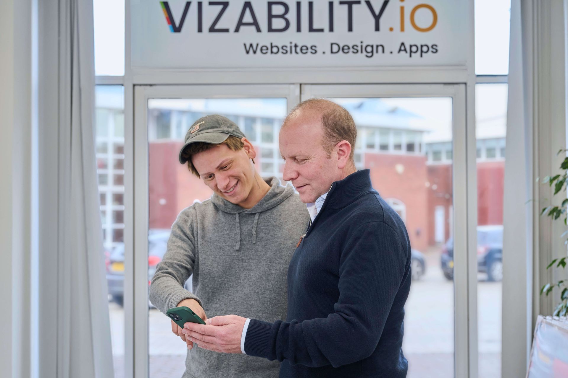 Two men looking at a phone in an office with
