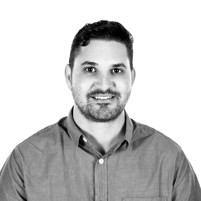 A man with a beard is smiling in a black and white photo