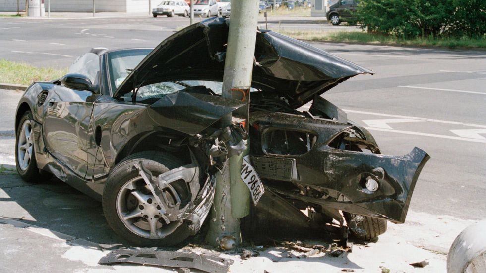 A car that has crashed into a pole with the hood up