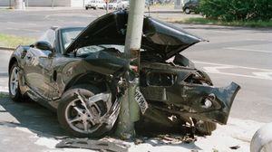 A car that has crashed into a pole with the hood up