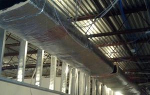 A large air duct is hanging from the ceiling of a building