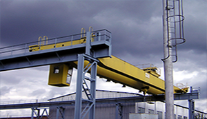 A yellow crane is sitting in front of a building with a cloudy sky in the background