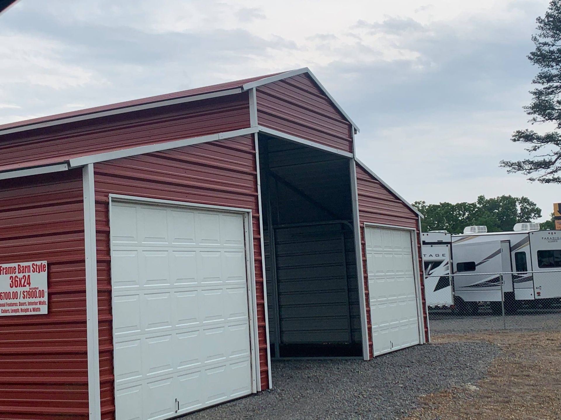 Red metal storage shed with white garage doors, outdoors.