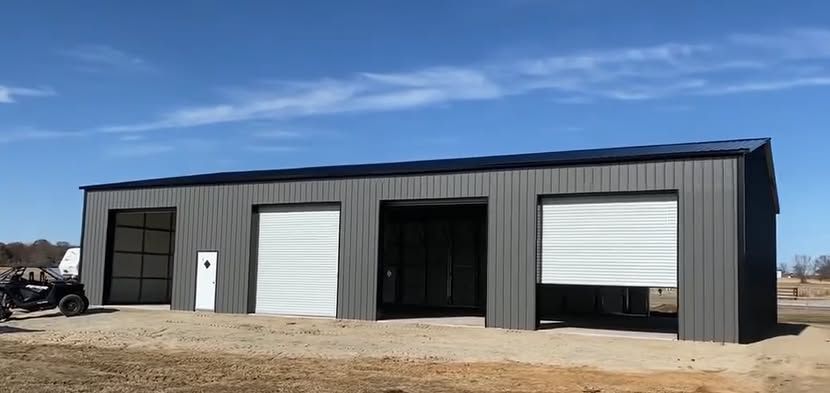 Gray garage building with three bays and a blue sky.