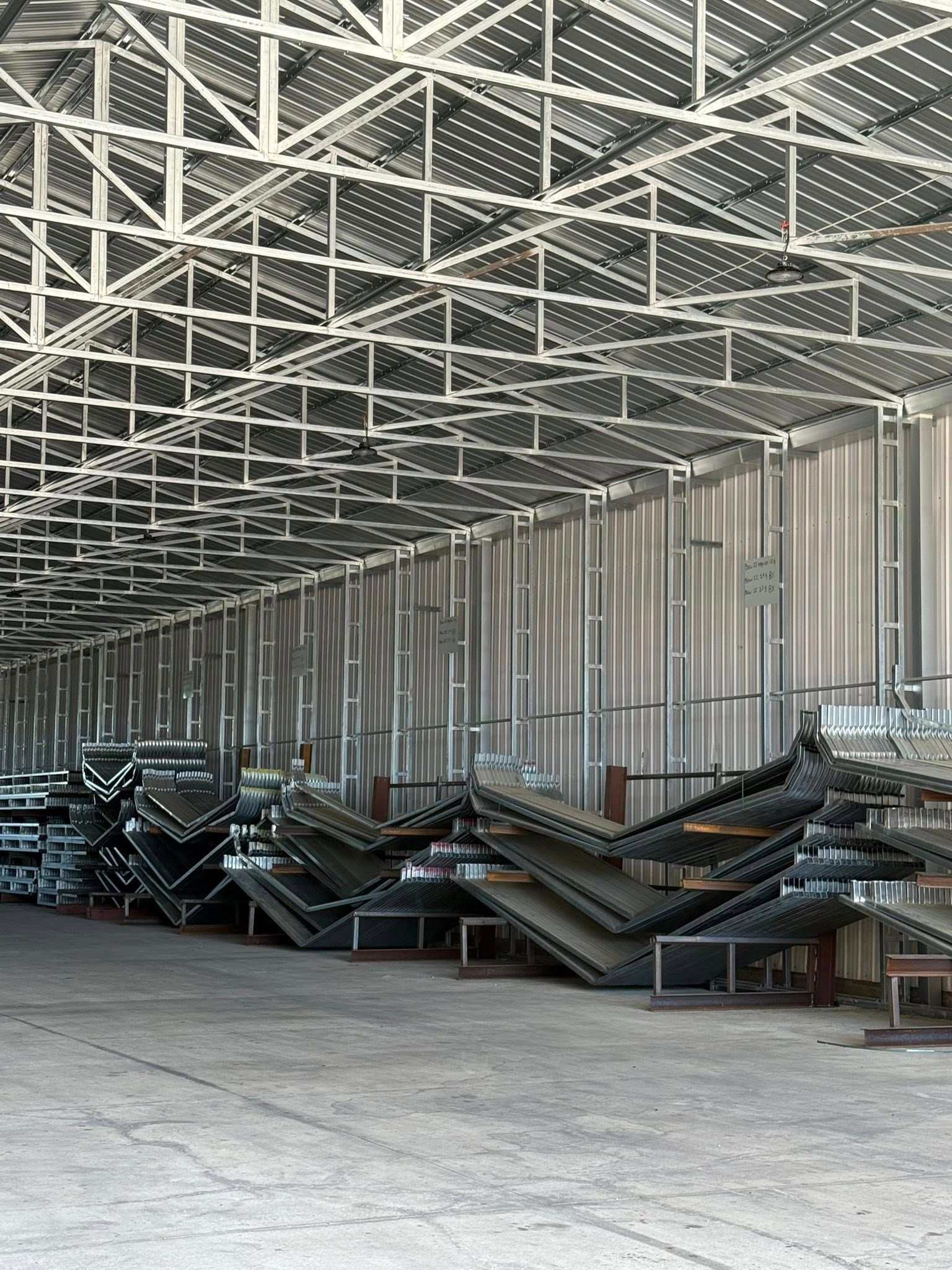 Steel-framed warehouse interior with stacked metal components and structural supports.